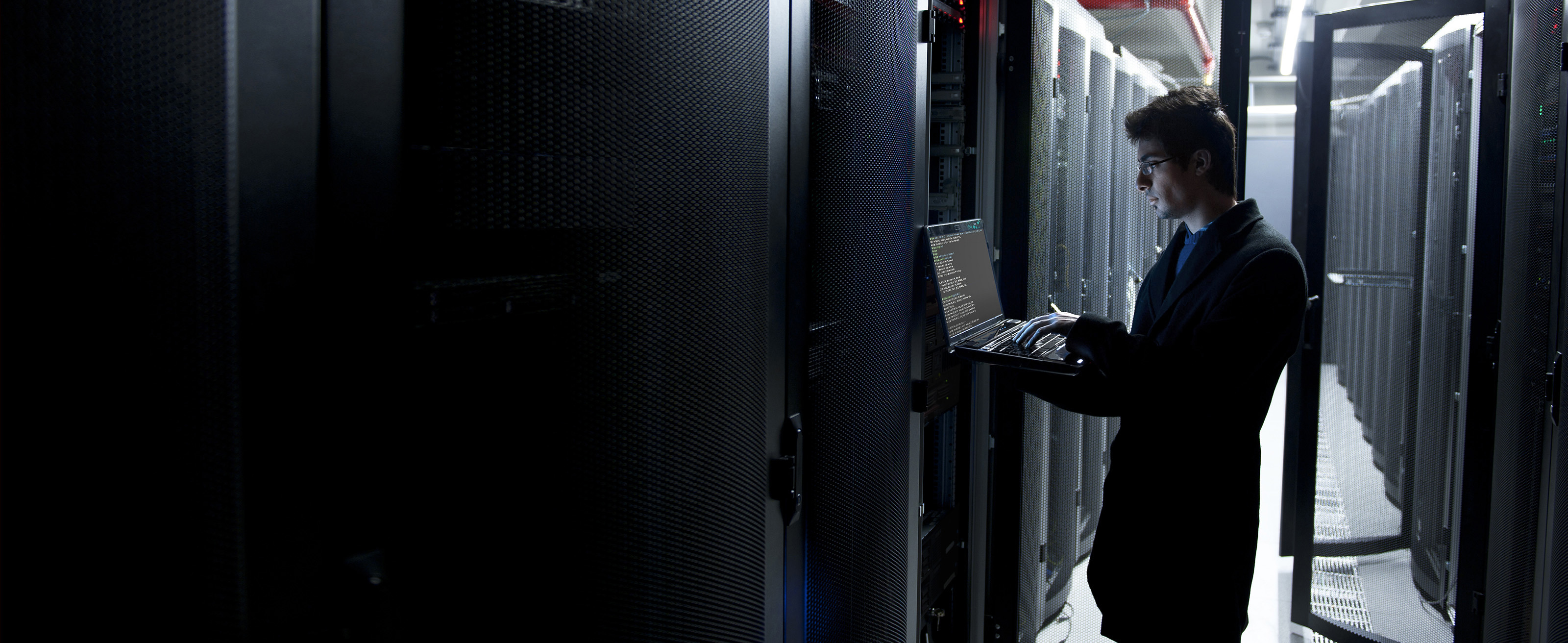 IT worker in enterprise data center working on the network via a laptop