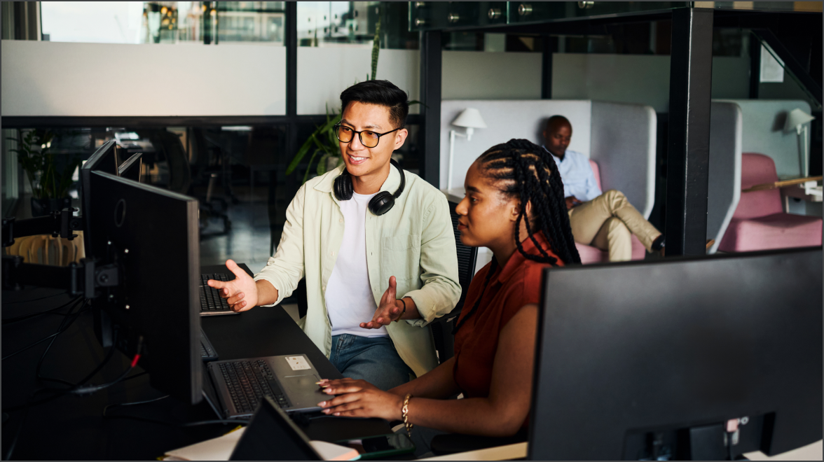 Two employes working at a desk on computers
