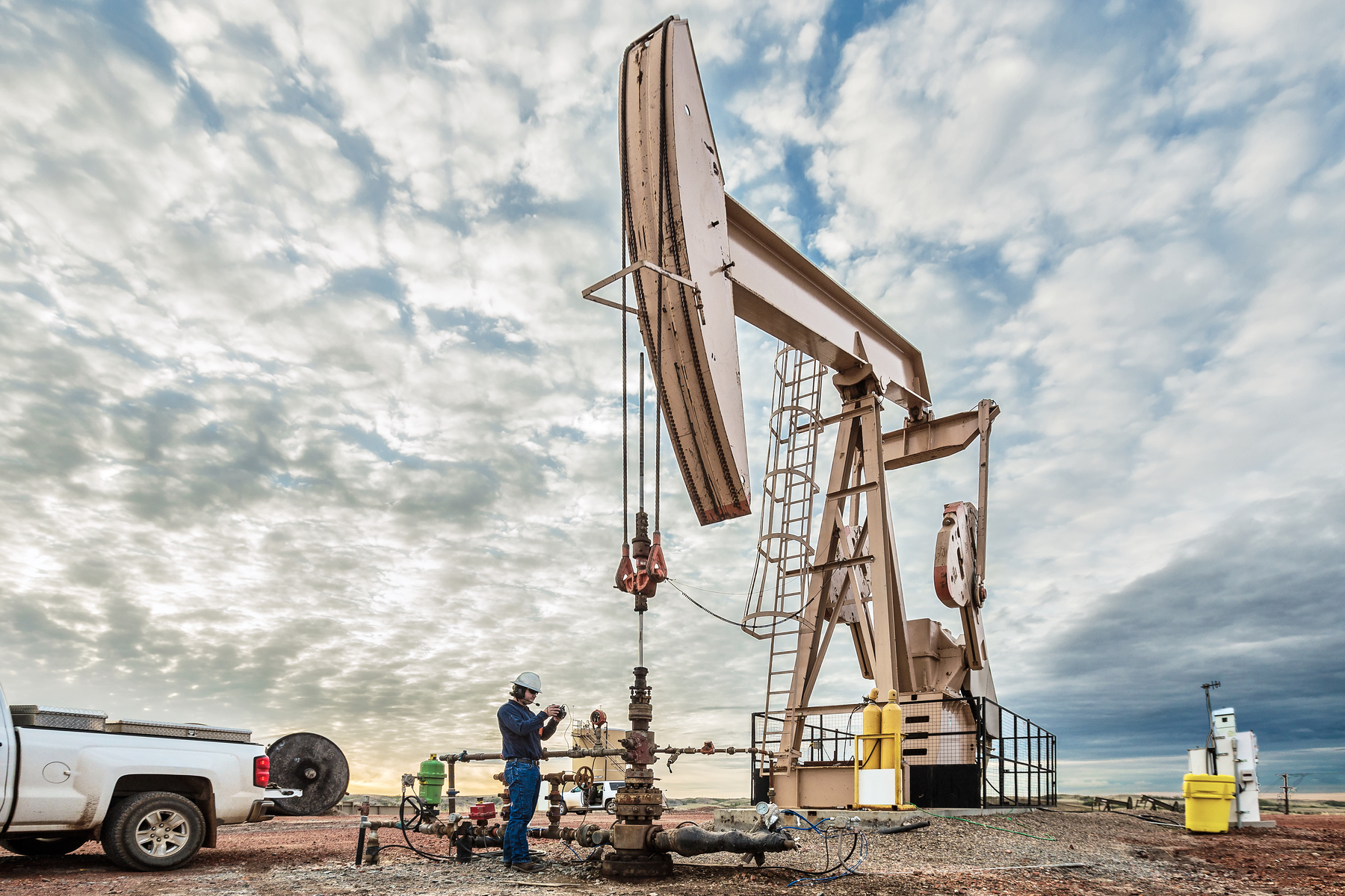 Worker on device in front of oil drill
