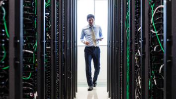 man staning in between rows of server racks